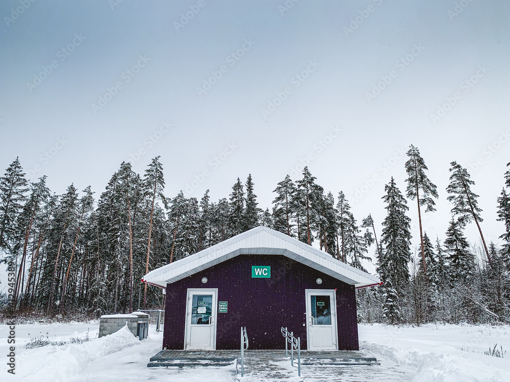 Public outdoor toilet wc in forest in winter. Woodland nature. Travel concept background. Countryside landscape. Rural scenery.