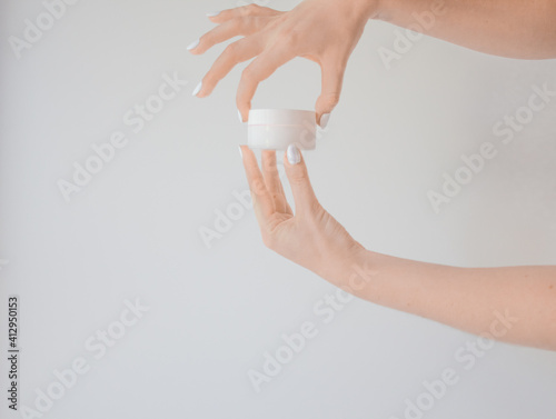 Plastic jar of cream in a female hand isolated on white. Professional cosmetics to restore skin youth, anti-aging cream. Skin care concept. Jar mockup. © Natali