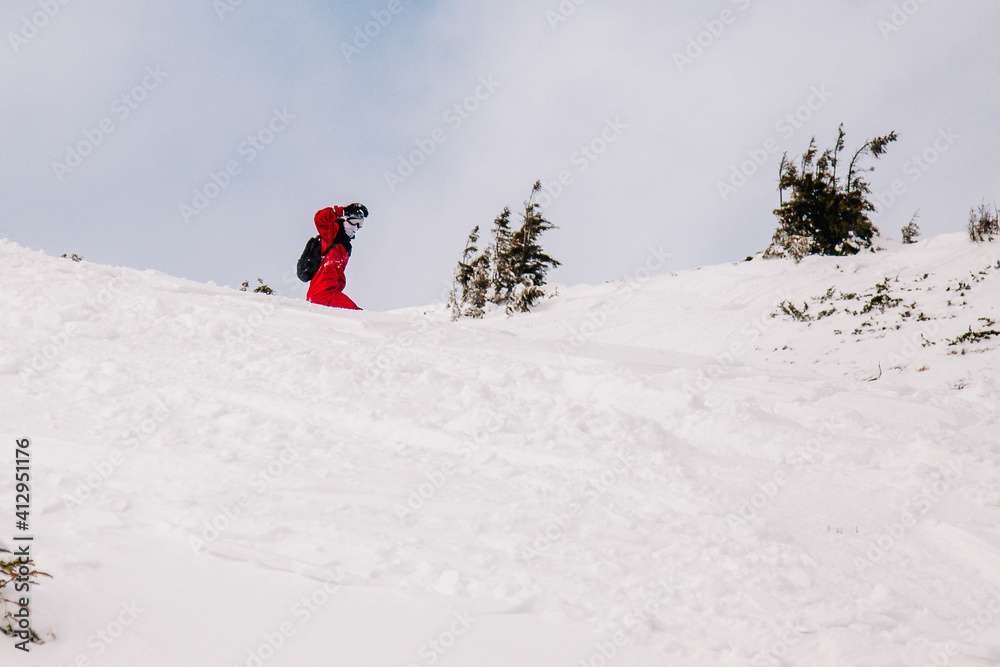 A guy in a red jumpsuit eating freeride on a snowboard on a snowy slope A guy in a red jumpsuit eating freeride on a snowboard on a snowy slope