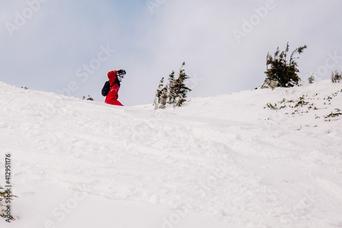 A guy in a red jumpsuit eating freeride on a snowboard on a snowy slope