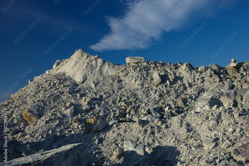 Heaps of limestone in a stone quarry against the background of a  dark blue sky, close-up.