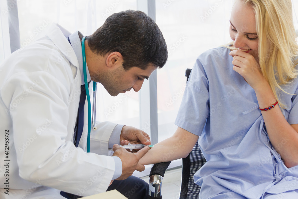 Fototapeta premium male doctor is using a syringe to inject a female patient