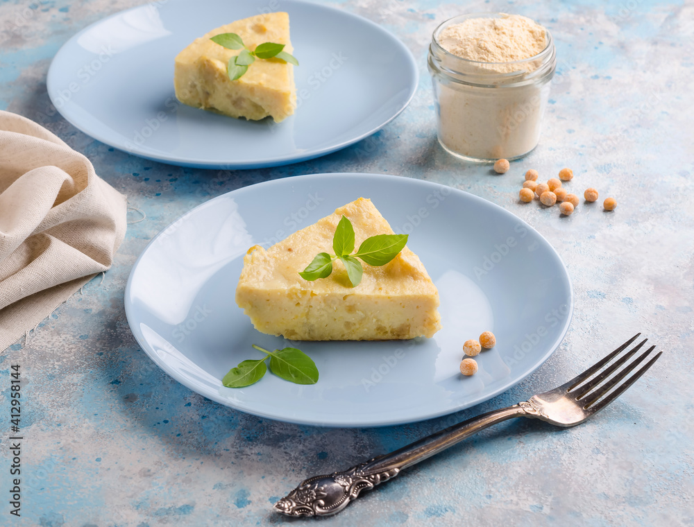 Slice of veggie pea flour omelet and basil herbs on blue background