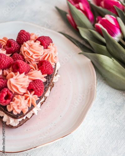 Cake in the shape of a heart from Traditional French dessert eclair and Pavlov cookies on a white background with tulips. Valentine's day concept