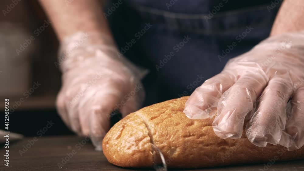 Male hands slicing bread, close-up. Chef complies with safety measures during the Covid-19 pandemic using antibacterial gloves. Male hands slicing bread, close-up. Chef complies with safety measures during the Covid-19 pandemic using antibacterial gloves.