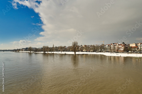 Heidelberg, Germany - Gray clouds covering blue sky over snow covered Neckar riverbank in winter © Firn