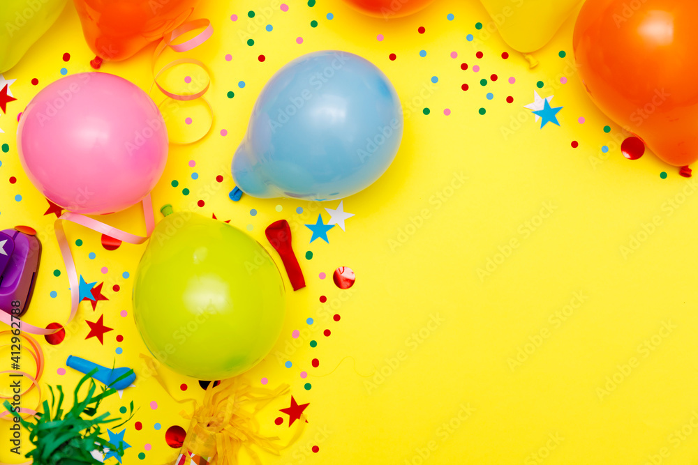Colorful balloons and confetti on yellow table top view. Festive or party background. Flat lay style. Birthday greeting card. Carnival. Colorful balloons and confetti on yellow table top view. Festive or party background. Flat lay style. Birthday greeting card. Carnival.