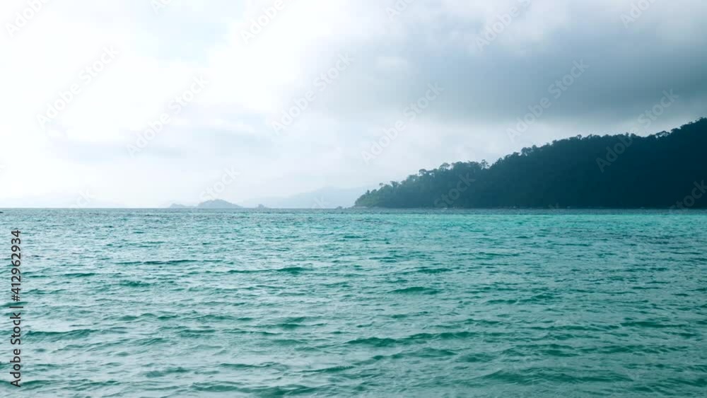 Turquoise Sea Water on Tropical Beach with Clouds and Green Island with Palms on Background. Relax on Beautiful Ocean Rainy Day. Vacation on Famous Travel Destination - Koh Lipe Island, Thailand Turquoise Sea Water on Tropical Beach with Clouds and Green Island with Palms on Background. Relax on Beautiful Ocean Rainy Day. Vacation on Famous Travel Destination - Koh Lipe Island, Thailand