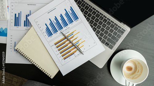 A graph placed on a laptop computer with a coffee cup on the black table in the office