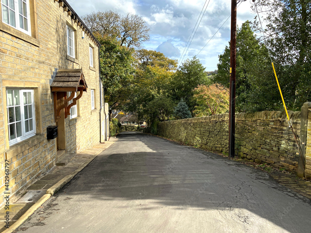 Looking down, Butterworth Lane, with dry stone walls, trees, and houses, on a cloudy autumn day near, Sowerby Bridge, UK