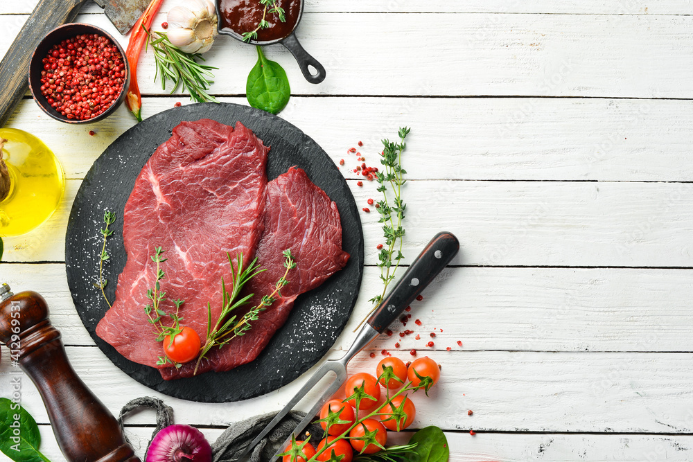 Two pieces of fresh raw veal with rosemary and spices. On a white wooden background. Top view. - obrazy, fototapety, plakaty 