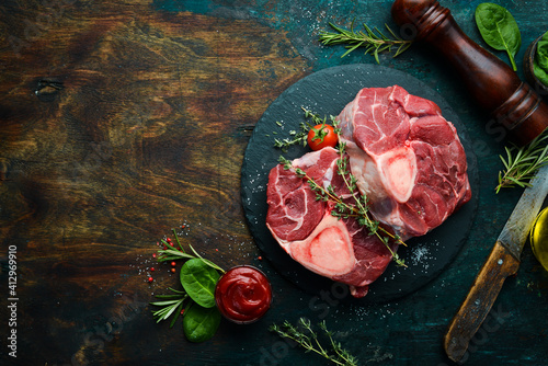 Fresh meat. Ossobuko steak on the bone with rosemary and spices. On a black stone background. Top view.