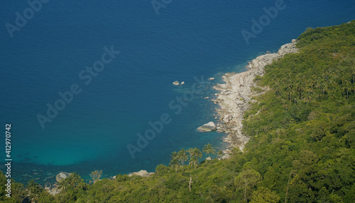 Trpoical rocky bay view Deep blue sea water with jungle palm trees photo