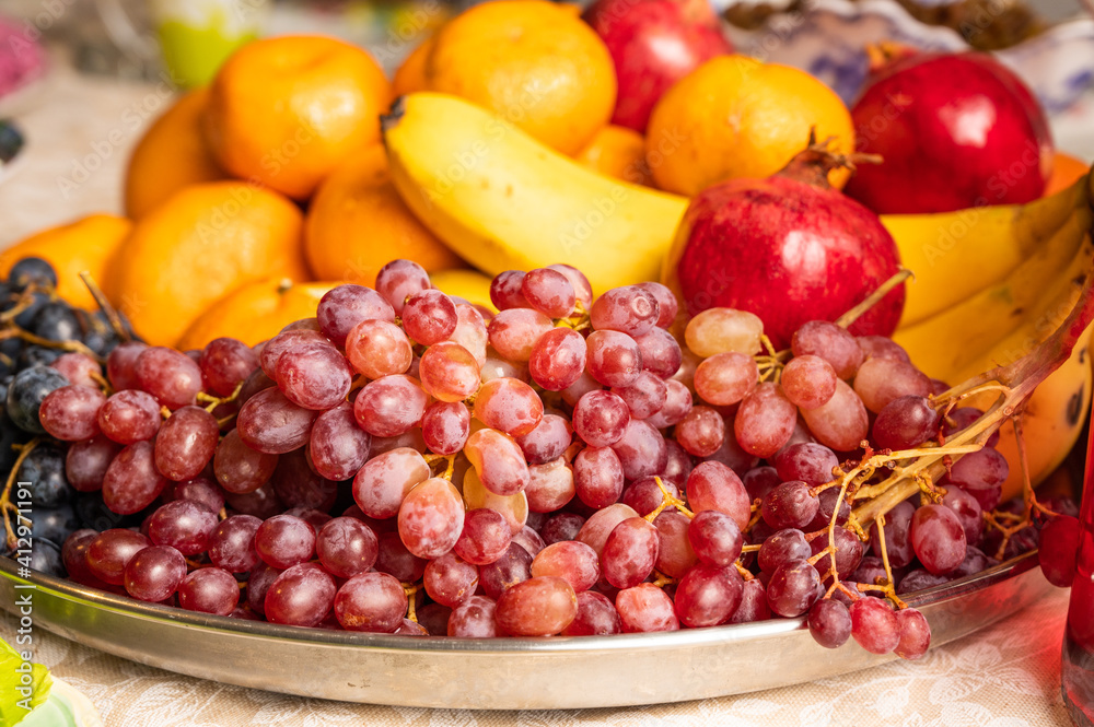 Fruit plate with grapes, pomegranates, tangerines and bananas Fruit plate with grapes, pomegranates, tangerines and bananas