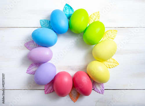 Easter colorful eggs in the form of a wreath on a light wooden background. Easter concept.