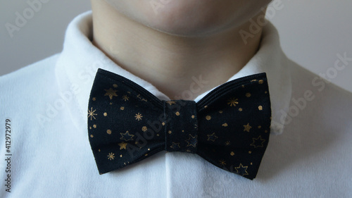 A boy in a festive white shirt and elegant black bow tie. The concept of a holiday, birthday, men's day, graduation