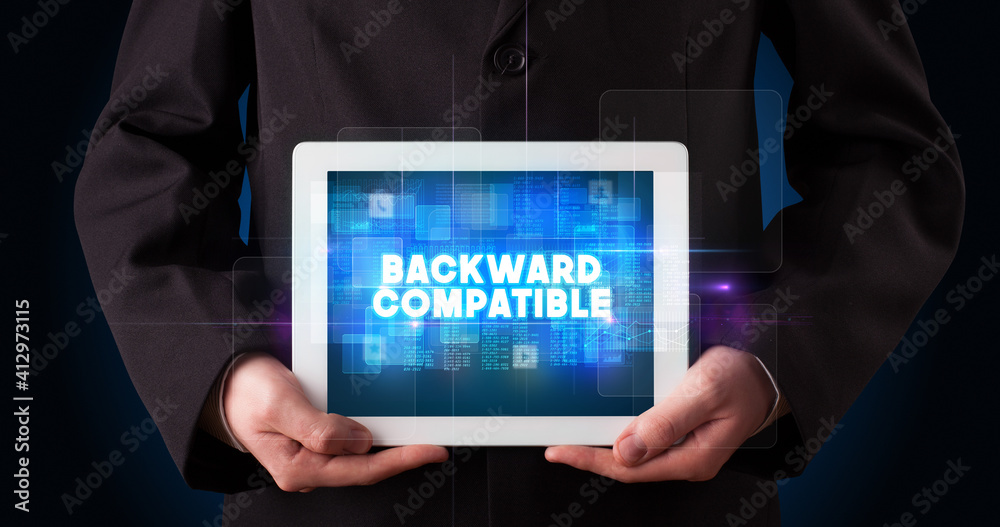Young business person working on tablet and shows the inscription: BACKWARD COMPATIBLE Young business person working on tablet and shows the inscription: BACKWARD COMPATIBLE