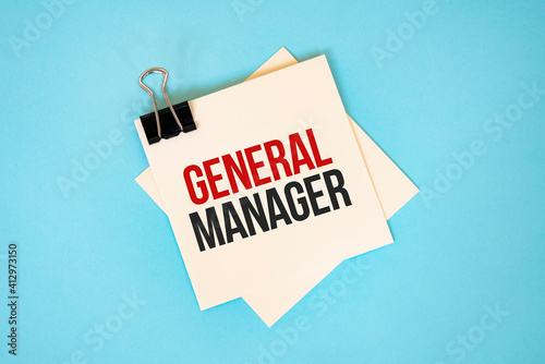 Text GENERAL MANAGER on sticky notes with copy space and paper clip isolated on red background.Finance and economics concept.