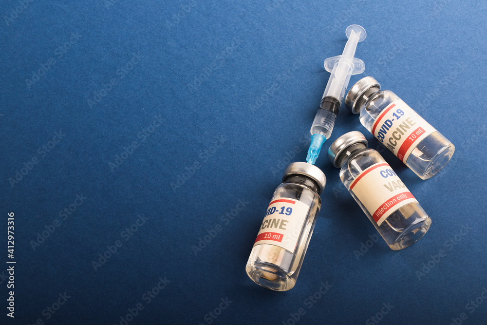 Naklejka premium COVID-19 vaccine. Medical bottles with liquid on blue.