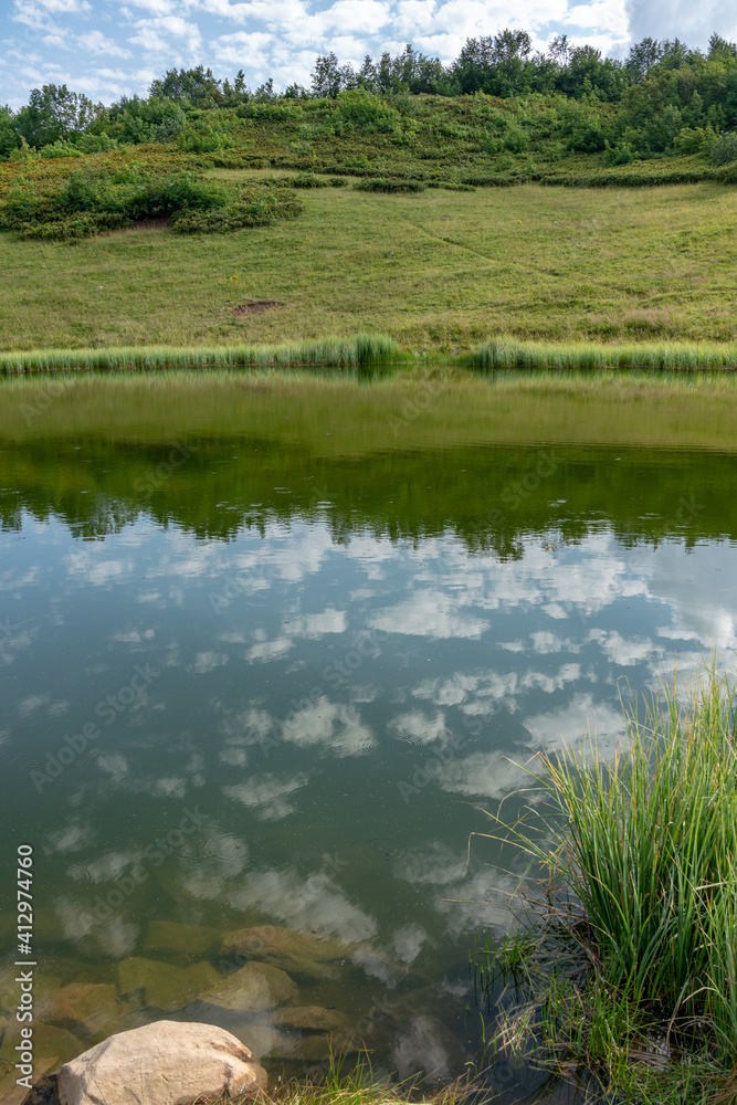 Mountain lake on the green top of the slope with the sky reflected in it with clouds. Mountain lake on the green top of the slope with the sky reflected in it with clouds.