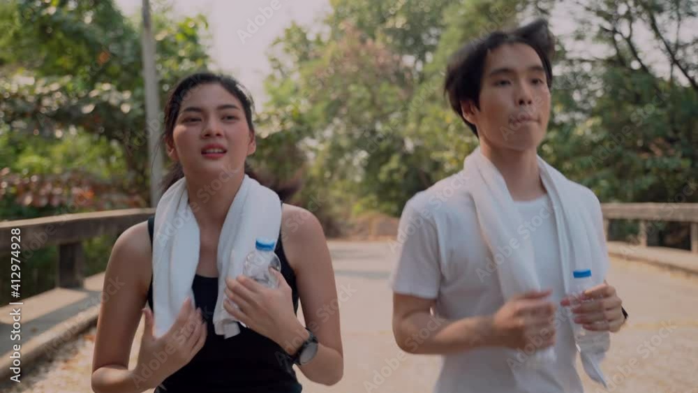 Asian couple young fit sport woman running and jogging in the park feeling sick during workout. girl feels have chest pain. She stops exercise due to have chest pain. Sickness and health care concept. Asian couple young fit sport woman running and jogging in the park feeling sick during workout. girl feels have chest pain. She stops exercise due to have chest pain. Sickness and health care concept.