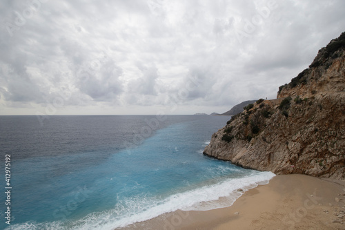 Wide angle seascape with hill, waves, turquoise sea and beach 