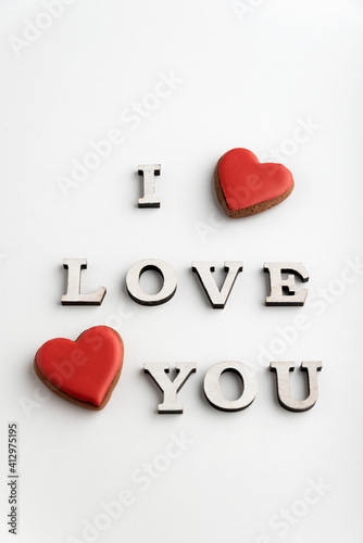 Inscription I LOVE YOU and red heart shaped gingerbread, white background. Valentines day. Vertical frame