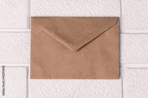 An envelope from old paper on a background of decorative white brickwork. Invitation mockup, vintage