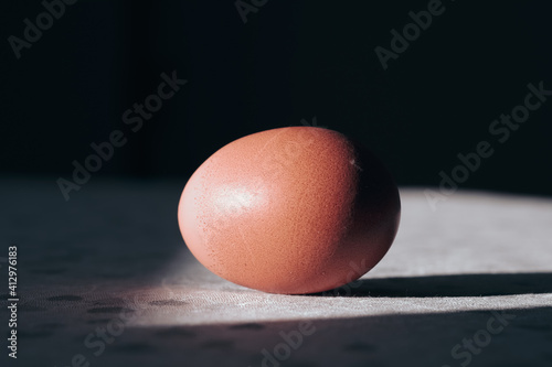 Brown egg with hard shadow on table. Creative Easter Christian tradition concept