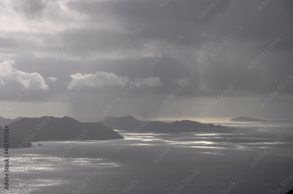 Ocean view over Praslin island with dramatic and overcast sky with sunbeam on the sea
