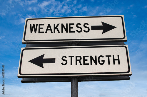 Road sign with words weakness and strength. White two street signs with arrow on metal pole. Directional road, Crossroads Road Sign, Two Arrow. Blue sky background