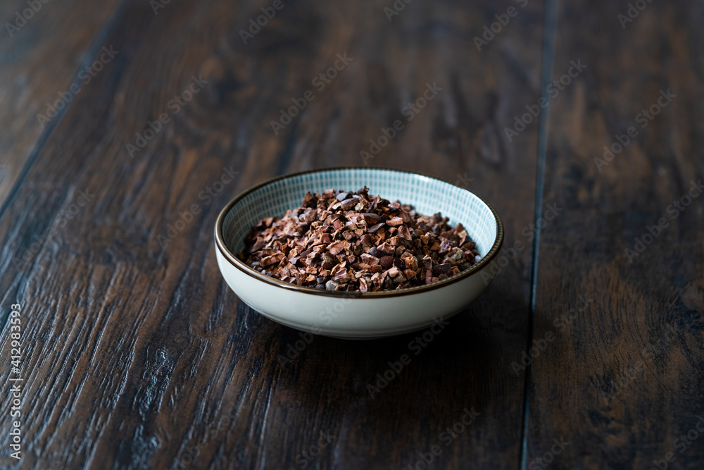 Chocolate Cacao Nibs or Cocoa Nibs in Bowl Ready to Use on Dark Wooden Surface. Chocolate Cacao Nibs or Cocoa Nibs in Bowl Ready to Use on Dark Wooden Surface.