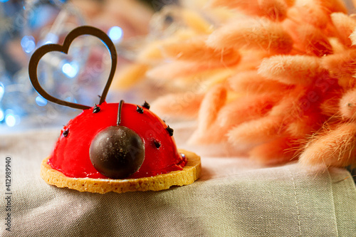 Ladybug sweet tasty colorful cake. Beautiful ladybug cake with chocolate heart on the lights background photo