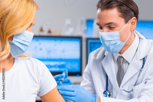 Professional doctor makes a coronavirus vaccine using a syringe and hypodermic needle. Professional medical worker and patient at the hospital office. Vaccination and safety.