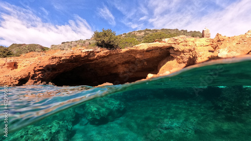 Underwater split photo from rocky sea cave formation in calm sea beach of Avlaki, Porto Rafti, Mesogeia, Attica, Greece