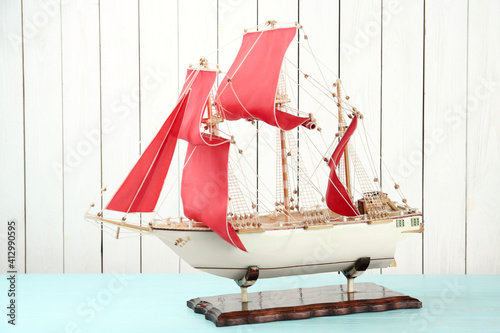 Leinwand Poster Beautiful ship model on light blue wooden table