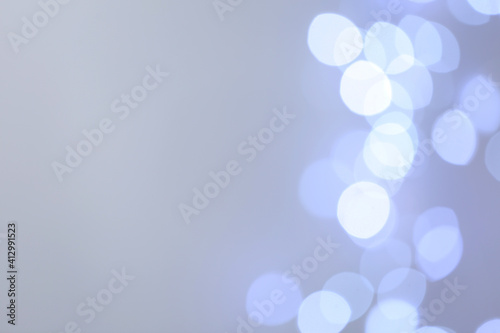 Blurred view of beautiful lights on light grey background, space for text