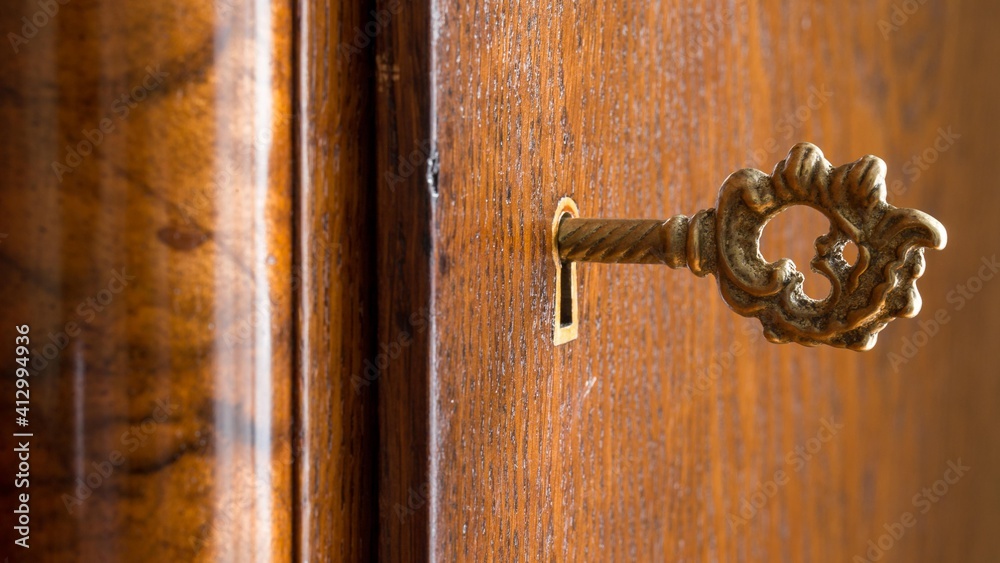 Old key in a keyhole of an old wooden wardrobe . Security concept. Wood detail Old key in a keyhole of an old wooden wardrobe . Security concept. Wood detail