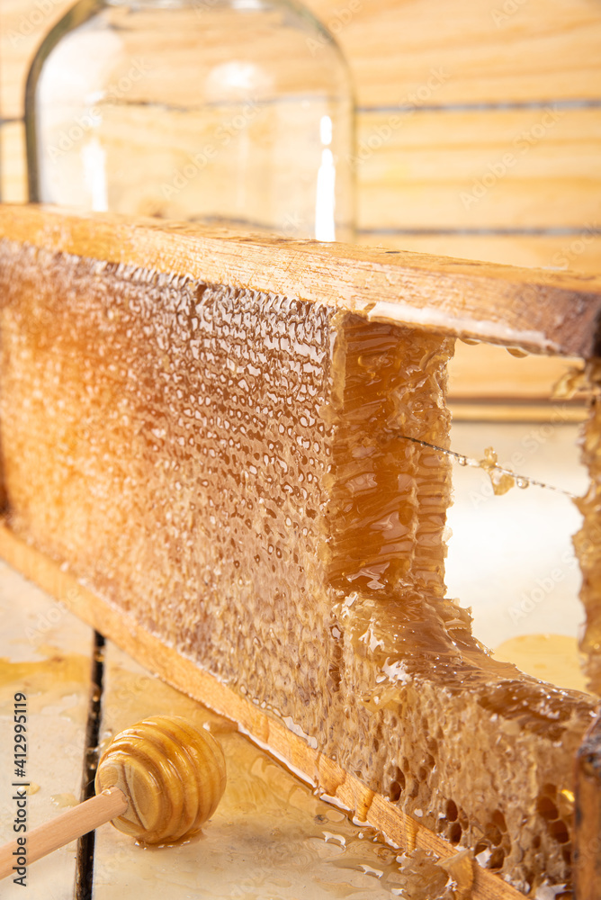 Honeycomb, honeycombs in the wooden frame and honey server. Wooden background, selective focus. Honeycomb, honeycombs in the wooden frame and honey server. Wooden background, selective focus.