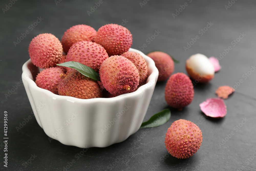 Fresh ripe lychee fruits in white ceramic bowl on black table Fresh ripe lychee fruits in white ceramic bowl on black table