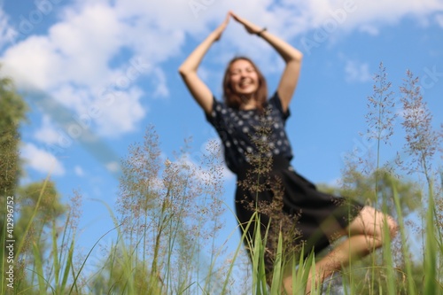 outdoor sports in summer. yoga class in the field. lonely woman goes in for sports on the background of the sky in the grass. blurred photo, selective focus