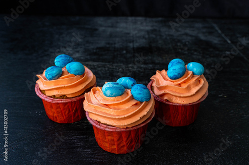 Easter cupcake with whipped orange cream. decorated with blue easter eggs. low key. Copy spece photo