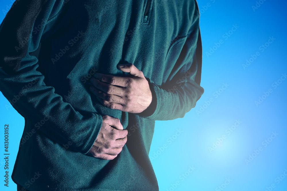 Man holds his belly with both hands against a blue background. Man holds his belly with both hands against a blue background.