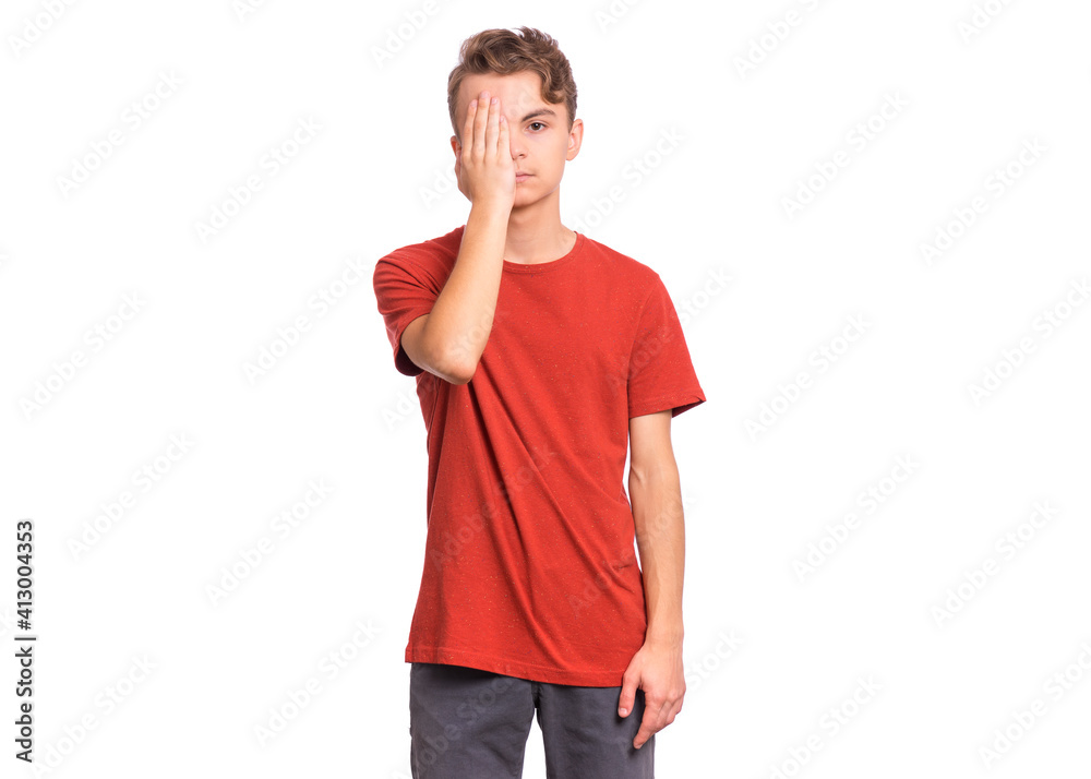 Fototapeta premium Sad handsome teen boy looks with one eye while covering his other eye with his hand, isolated on white background