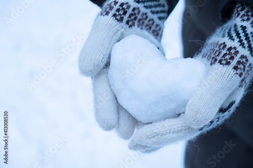 Snowy heart close up in hands. Love symbol for valentine's day and eighth march