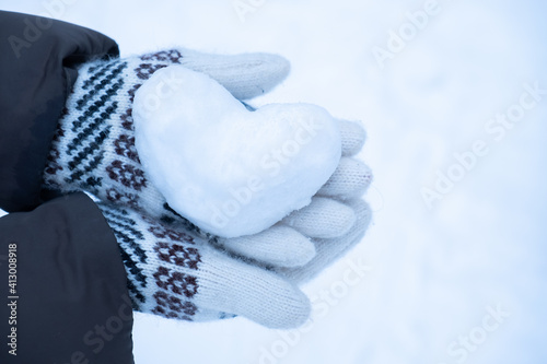 Snowy heart close up in hands. Love symbol for valentine's day and eighth march