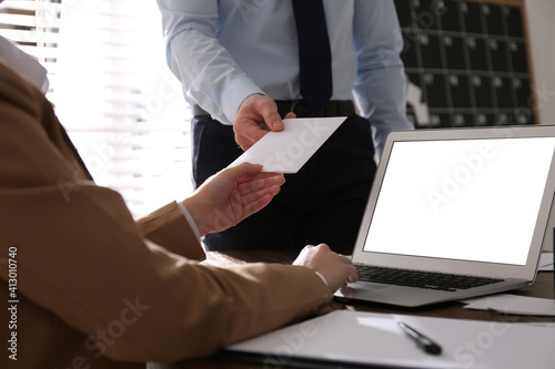 Employee giving resignation letter to boss in office, closeup