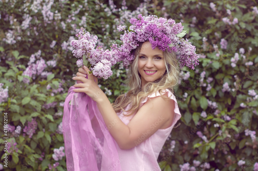 Blonde woman enjoying in a spring garden with blooming lilacs with bouquet, lilac flowers hair style. Spring Concept, Spring blossom, Positive human emotions and feelings. Blonde woman enjoying in a spring garden with blooming lilacs with bouquet, lilac flowers hair style. Spring Concept, Spring blossom, Positive human emotions and feelings.