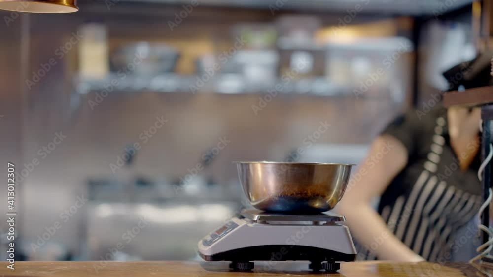 Close-up of metal bowl on scales with blurred Caucasian cook in Covid-19 face mask putting greenery inside in slow motion. Young woman working in cafeteria on coronavirus pandemic. Close-up of metal bowl on scales with blurred Caucasian cook in Covid-19 face mask putting greenery inside in slow motion. Young woman working in cafeteria on coronavirus pandemic.