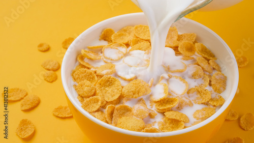 Milk pouring into bowl of corn flakes